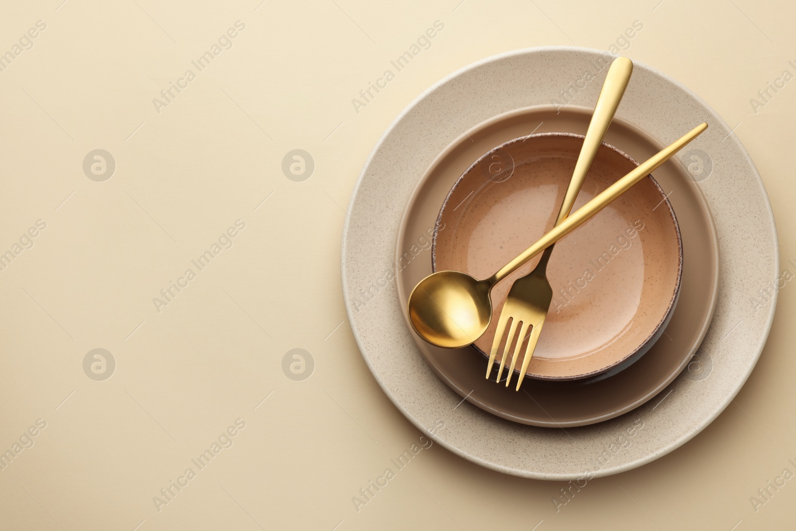 Photo of Stylish empty dishware and cutlery on beige background, top view. Space for text