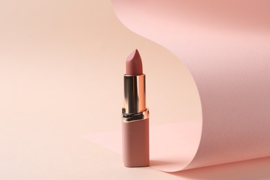 Photo of Beautiful lipstick on beige background. Professional makeup product
