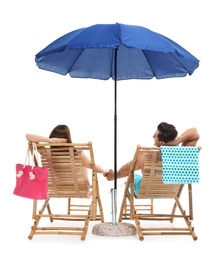 Photo of Young couple with beach accessories on sun loungers against white background