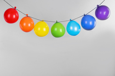 Photo of Garland with colorful air balloons on light blue background. Rainbow palette