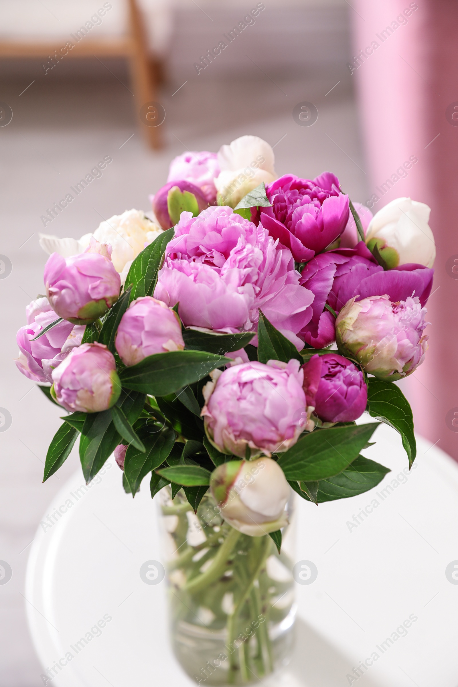 Photo of Vase with bouquet of fresh peonies on table in room