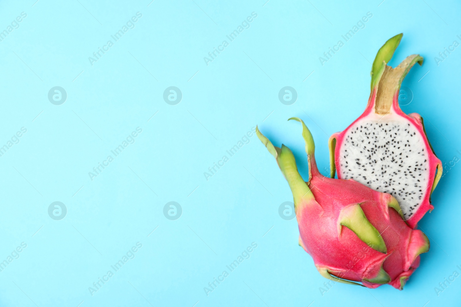 Photo of Halves of delicious ripe dragon fruit (pitahaya) on light blue background, flat lay. Space for text
