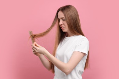 Photo of Emotional woman brushing her hair on pink background. Alopecia problem