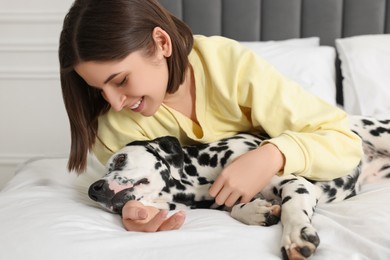 Photo of Beautiful woman with her adorable Dalmatian dog on bed at home. Lovely pet