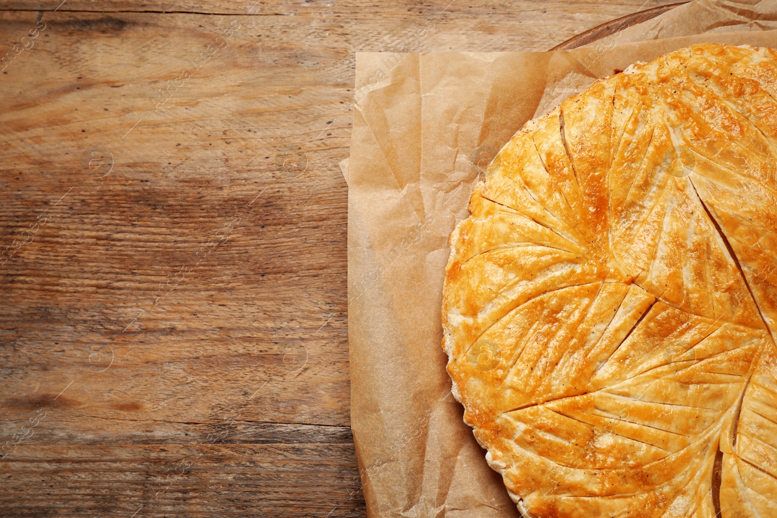 Photo of Traditional galette des rois on wooden table, top view. Space for text