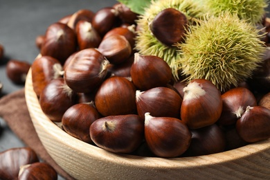 Fresh sweet edible chestnuts in wooden bowl, closeup