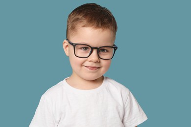 Photo of Cute little boy in glasses on light blue background