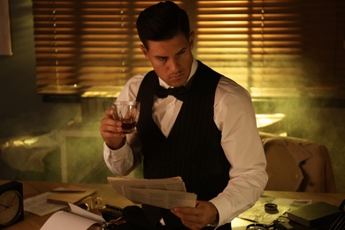 Photo of Old fashioned detective with drink and documents in office