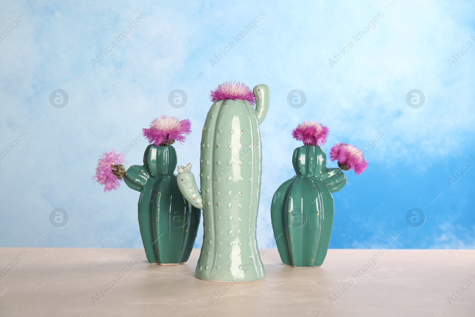 Photo of Trendy cactus shaped ceramic vases with flowers on table