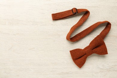Photo of Stylish terracotta bow tie on wooden background, top view. Space for text