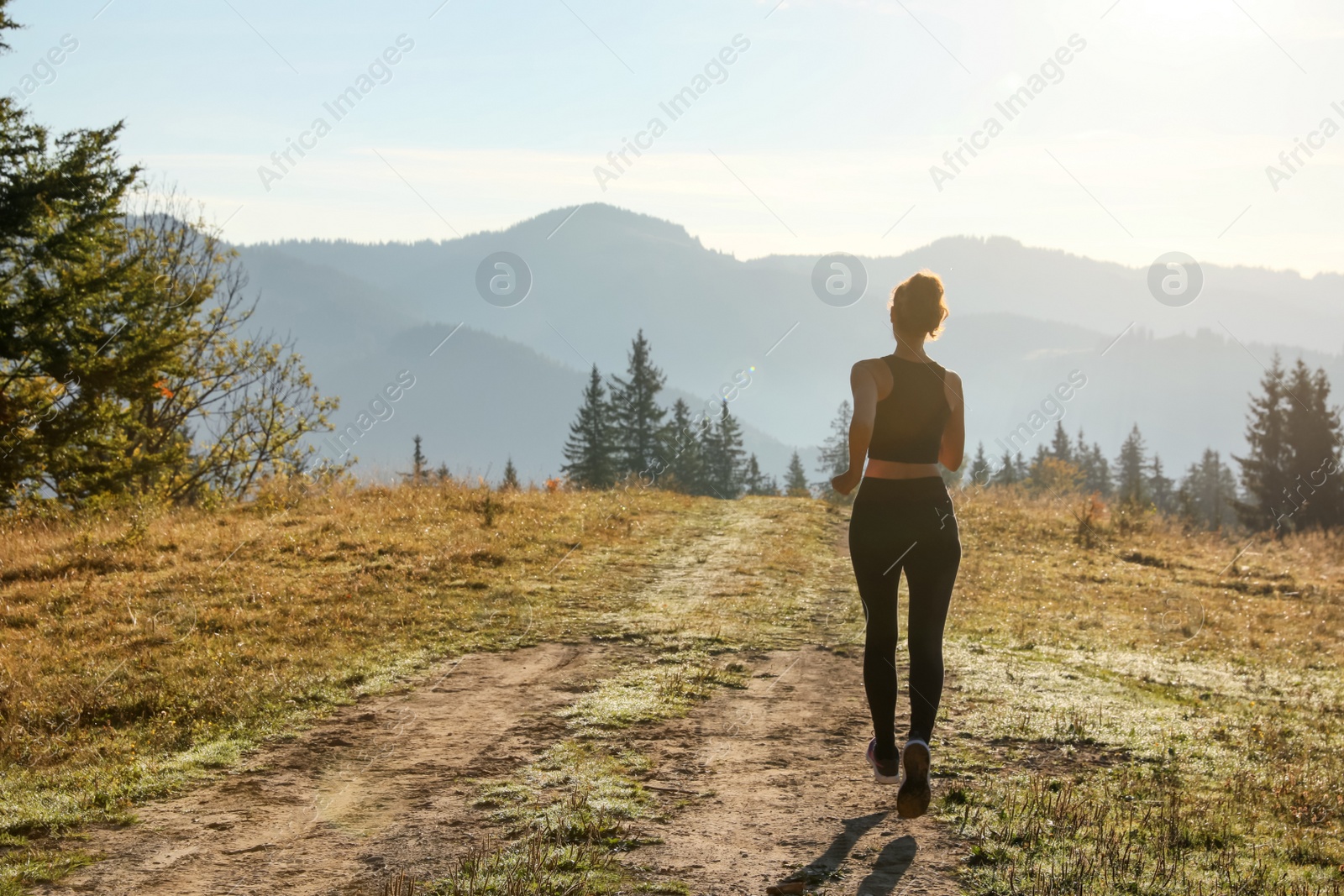 Photo of Sporty woman running in mountains, back view