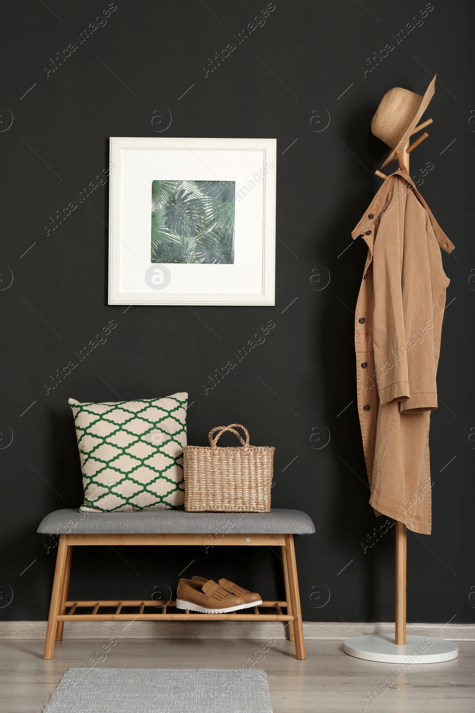 Photo of Bench with pillow and bag at black wall. Interior design