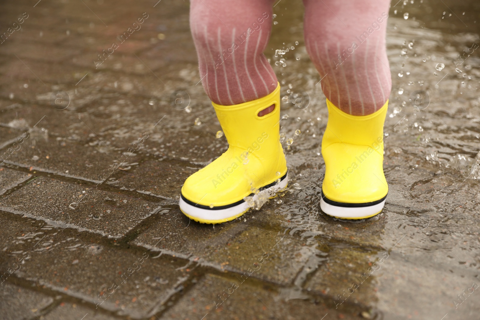 Photo of Girl walking in puddle outdoors on rainy weather, closeup