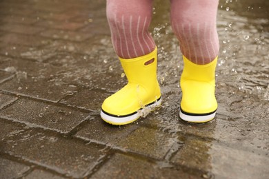 Photo of Girl walking in puddle outdoors on rainy weather, closeup