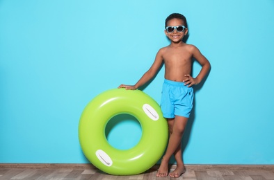 Cute African American boy with bright inflatable ring near color wall