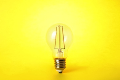 Vintage filament lamp bulb on yellow background