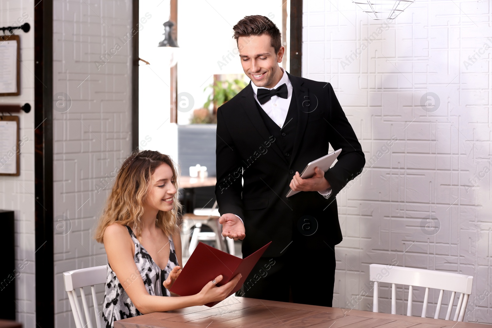 Photo of Young waiter taking order from client in restaurant