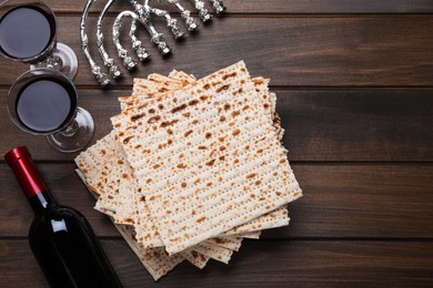 Photo of Matzos, red wine and menorah on wooden table, flat lay