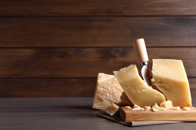Photo of Parmesan cheese with wooden board and knife on table. Space for text