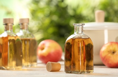 Photo of Composition with bottle of apple vinegar on table. Space for text