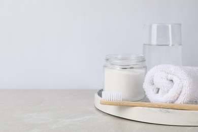 Bamboo toothbrush, jar of baking soda, towel and glass of water on light marble table, space for text