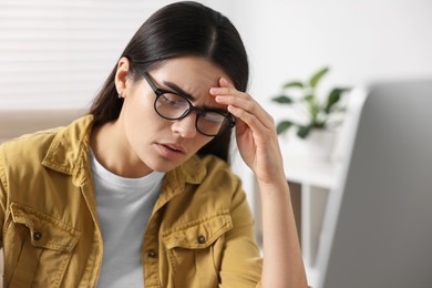 Photo of Young woman suffering from headache at workplace indoors