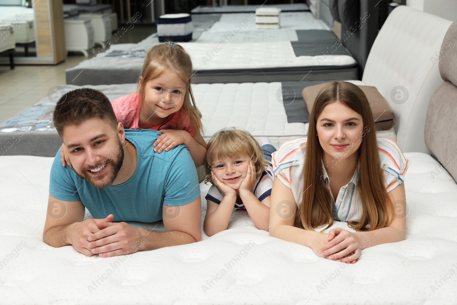 Photo of Happy family lying on new orthopedic mattress in store