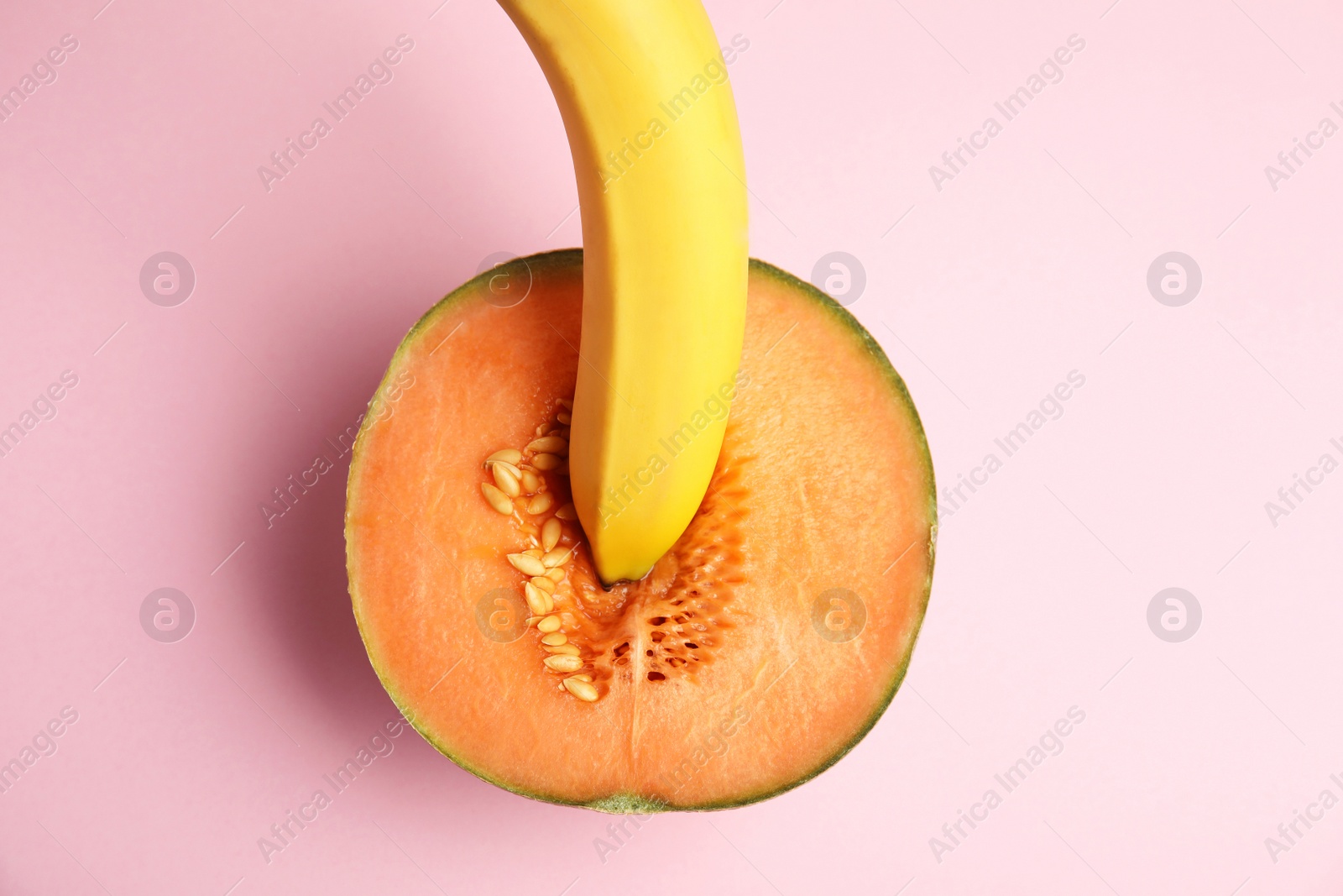 Photo of Flat lay composition with fresh banana and melon on pink background. Sex concept