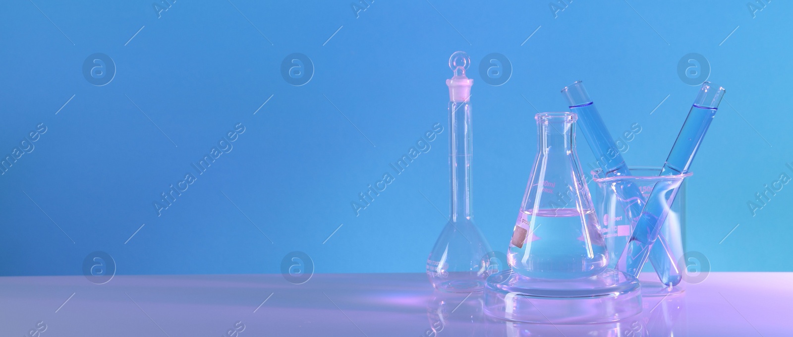 Photo of Laboratory analysis. Different glassware on table against light blue background, space for text