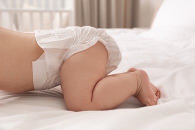 Photo of Little baby in diaper on bed at home, closeup