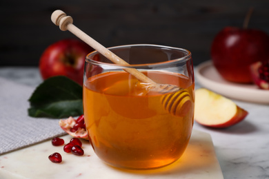 Photo of Honey, apples and pomegranate seeds on white marble table. Rosh Hashanah holiday