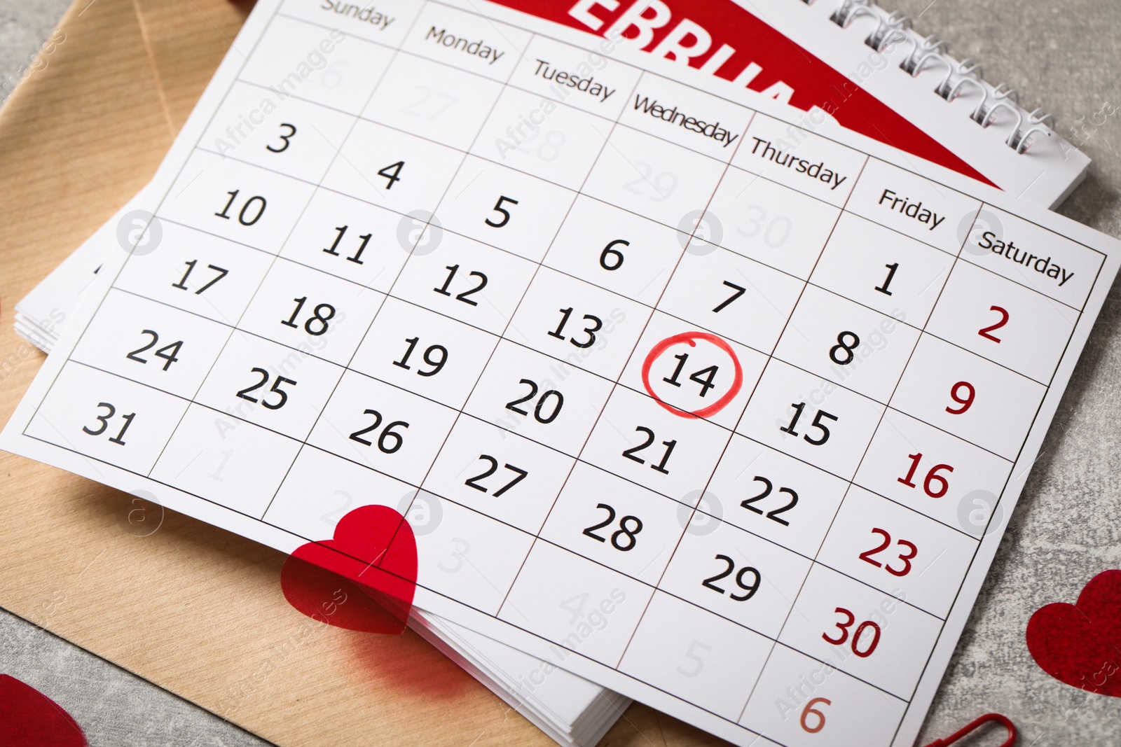 Photo of Calendar with marked Valentine's Day, envelope and hearts on grey table