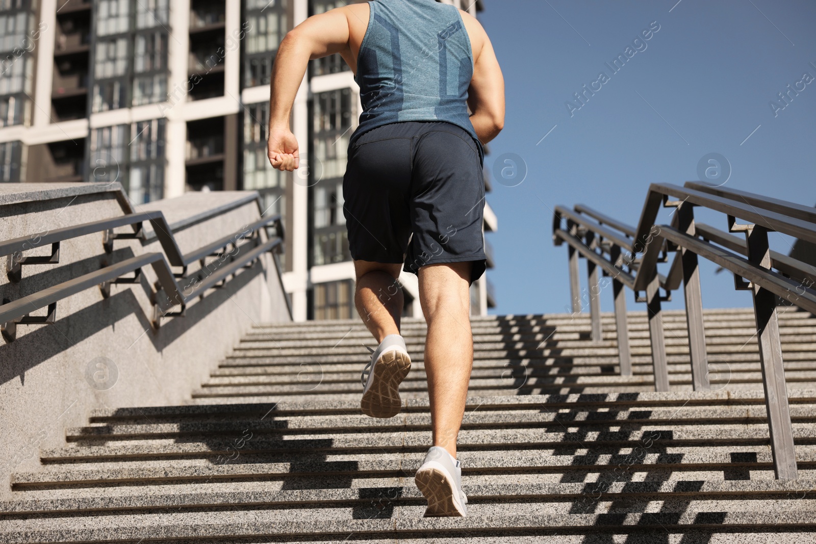 Photo of Man running up stairs outdoors on sunny day, closeup