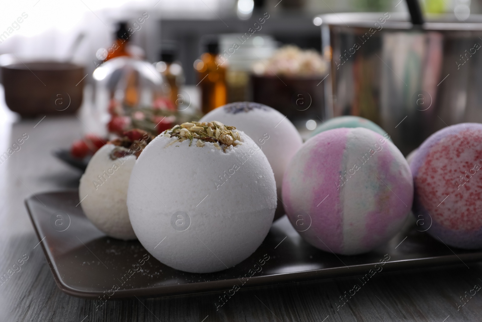 Photo of Plate with different bath bombs on wooden table, closeup