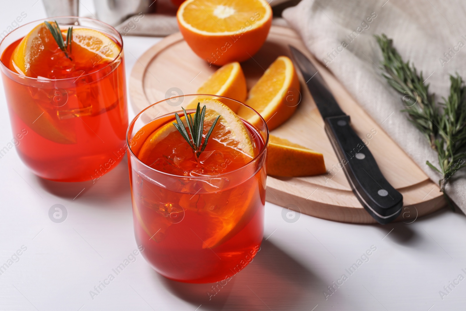 Photo of Aperol spritz cocktail, rosemary and orange slices on white wooden table