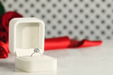Photo of Beautiful engagement ring with gemstone in box on white table. Space for text