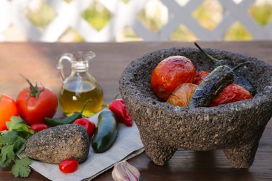 Photo of Ingredients for tasty salsa sauce, pestle and mortar on wooden table outdoors