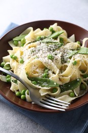 Photo of Delicious pasta with green peas and cheese served on grey table