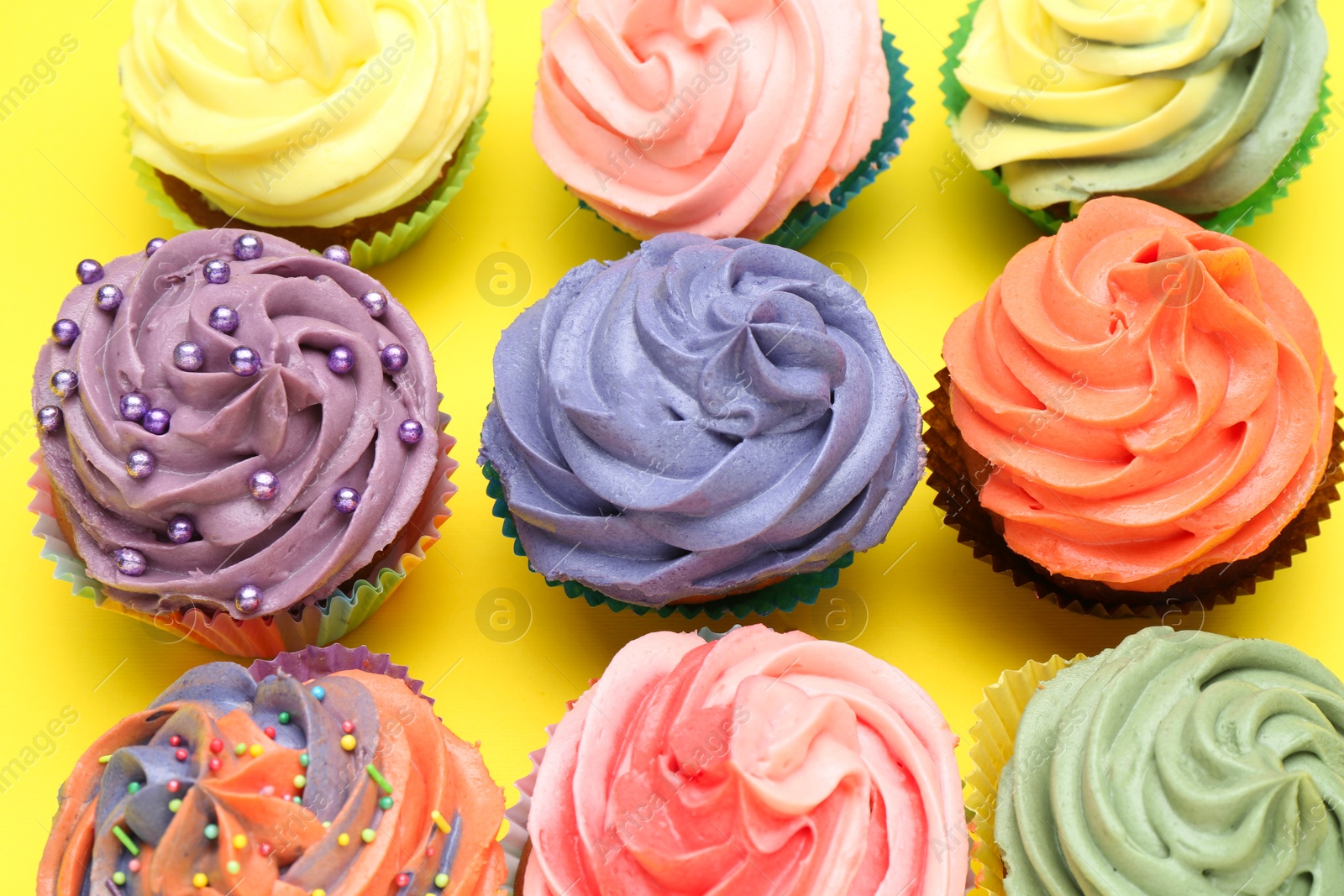 Photo of Delicious cupcake with bright cream on yellow background, flat lay