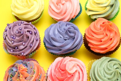 Photo of Delicious cupcake with bright cream on yellow background, flat lay