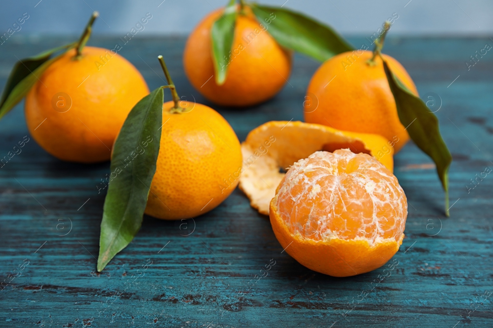 Photo of Fresh ripe tangerines with green leaves on table