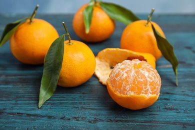 Fresh ripe tangerines with green leaves on table