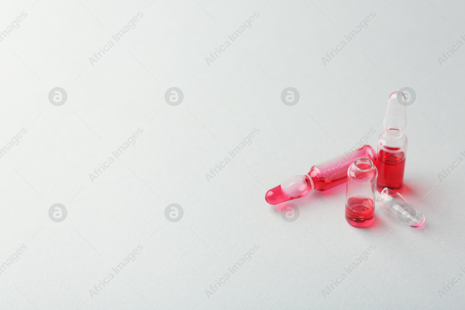 Photo of Glass ampoules with liquid on white background. Space for text