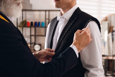 Professional tailor working with client in atelier, closeup