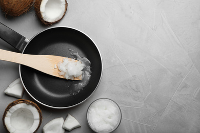 Flat lay composition with coconut oil and frying pan on grey table, space for text. Healthy cooking