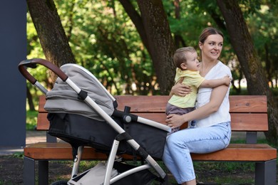 Photo of Beautiful nanny with cute little boy on bench in park