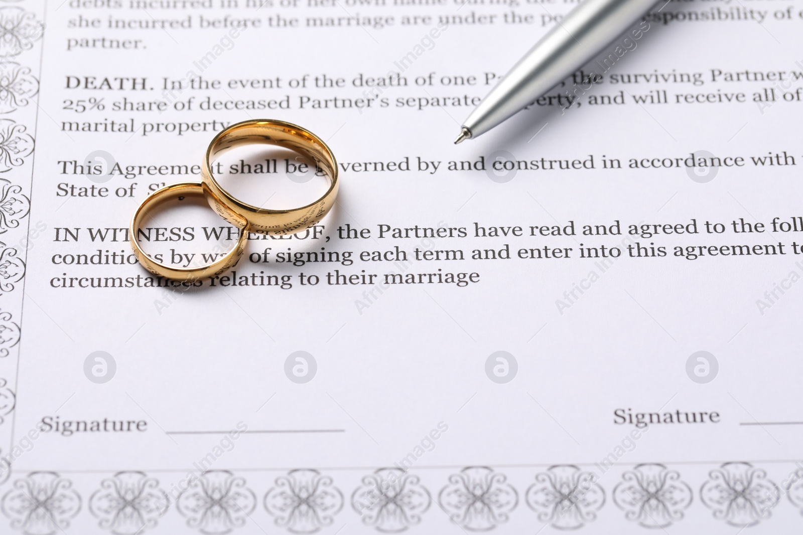 Photo of Marriage contract, gold rings and pen on table, closeup