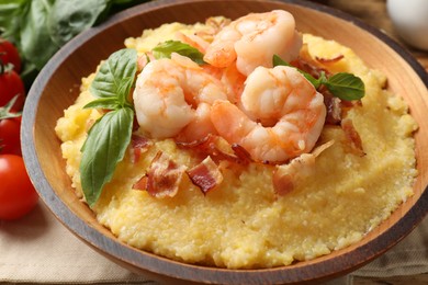 Photo of Fresh tasty shrimps, bacon, grits and basil in bowl on table, closeup