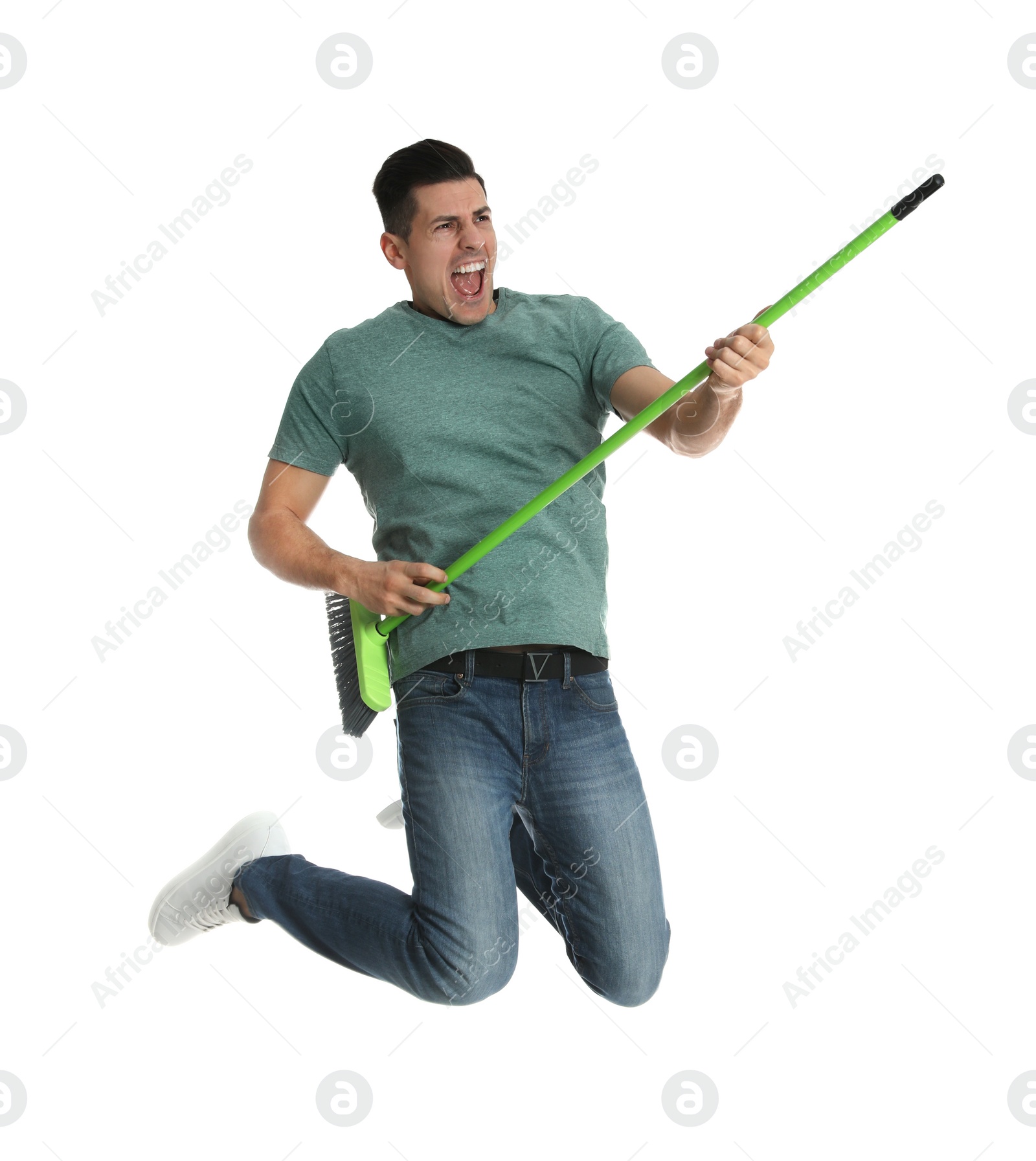 Photo of Man with green broom jumping on white background