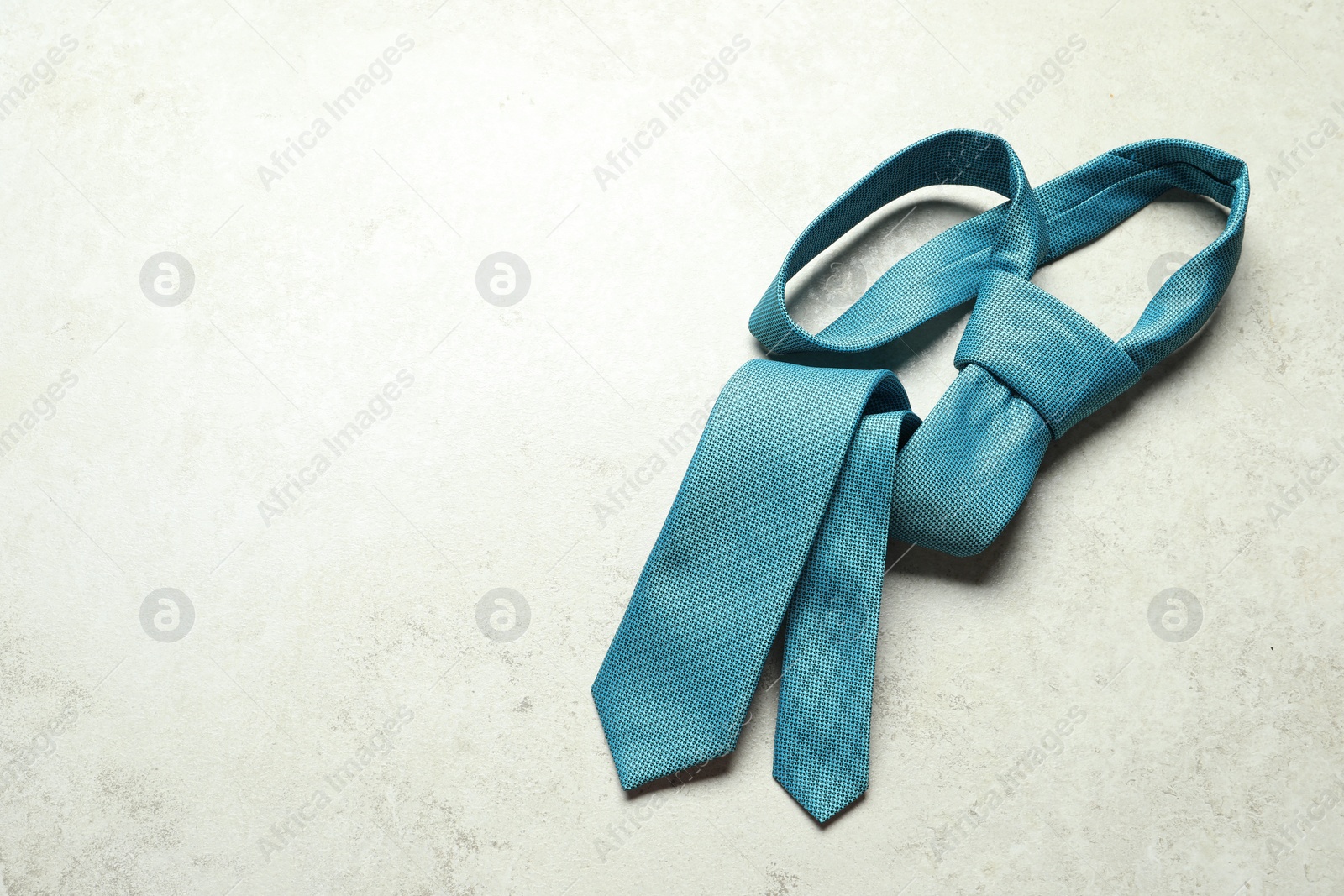 Photo of One blue necktie on light textured table, top view. Space for text